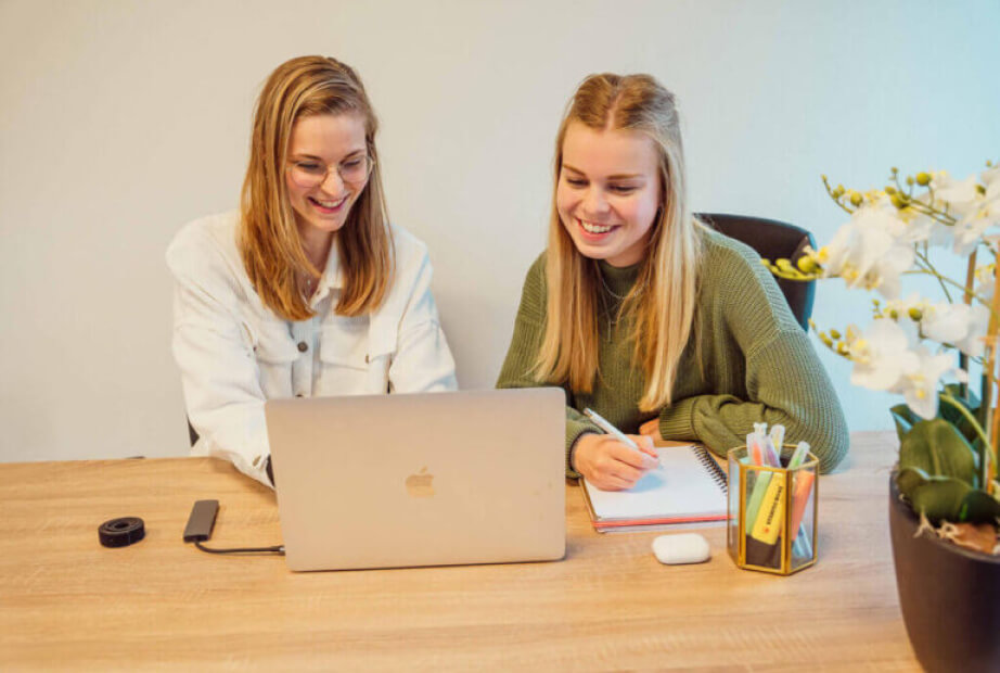 Sanne Daenen kijkt met haar collega bij Merk Maatjes naar haar laptop.